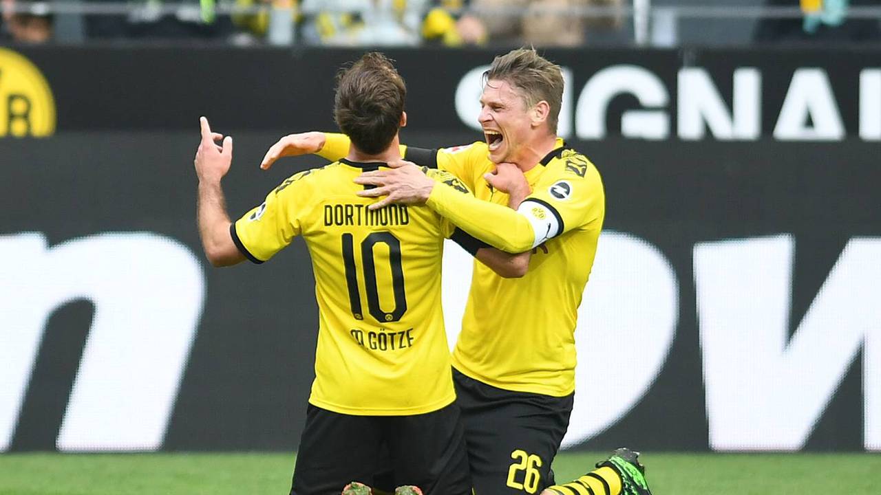 Mario Götze und Lukasz Piszczek knien auf dem Rasen, Piszczek will Götze umarmen.