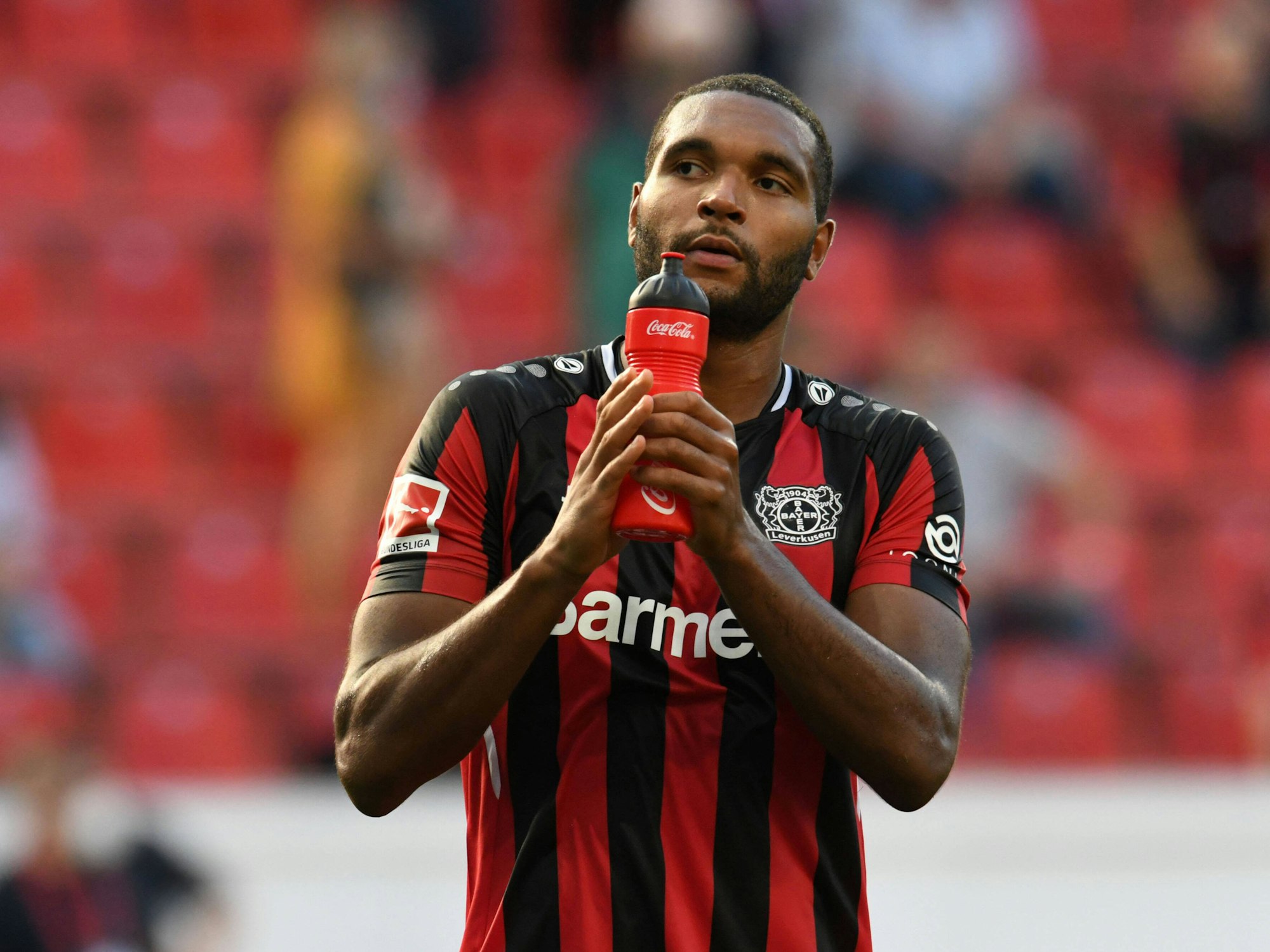 Jonathan Tah hält eine Trinkflasche in den Händen und applaudiert den Fans auf der Tribüne.