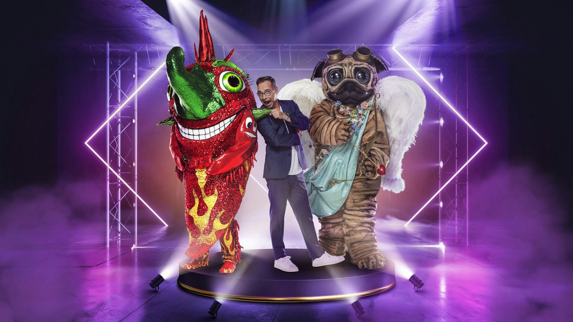 Matthias Opdenhövel mit den „The Masked Singer“-Kostümen aus der 5. Staffel, Chili und Mops.