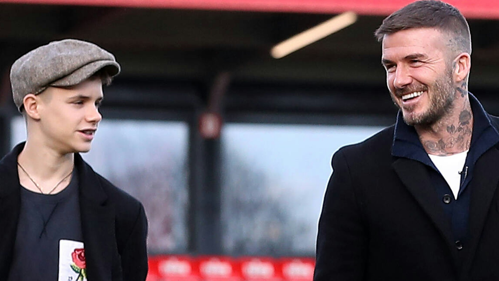 Romeo Beckham und David Beckham gehen auf dem Fußballplatz entlang.