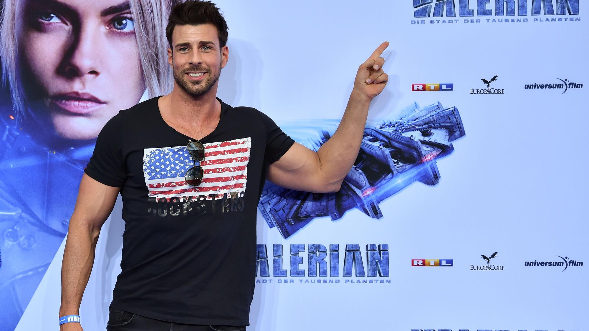 Leonard Freier steht vor dem Film-Plakat bei der Filmpremiere von „Valerian - Die Stadt der tausend Planeten“.