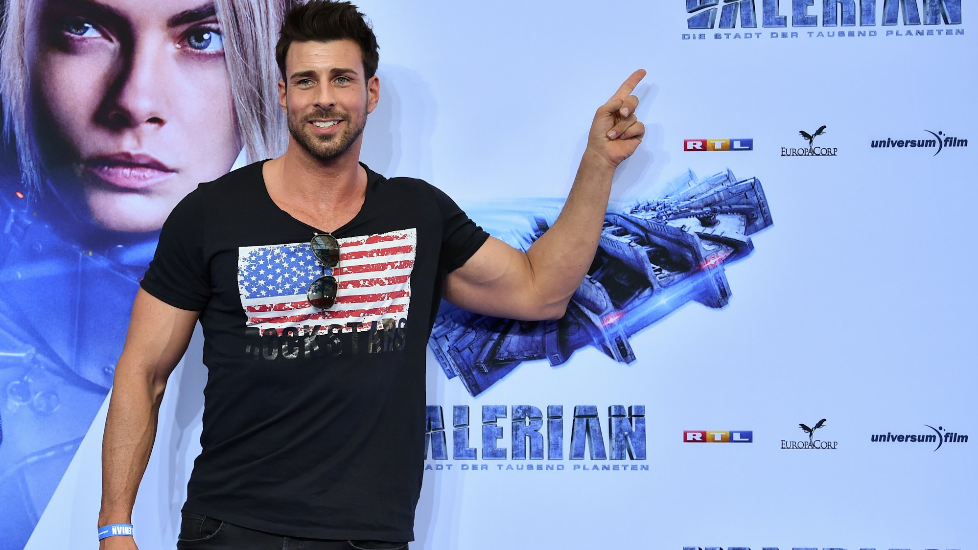 Leonard Freier steht vor dem Film-Plakat bei der Filmpremiere von „Valerian - Die Stadt der tausend Planeten“.