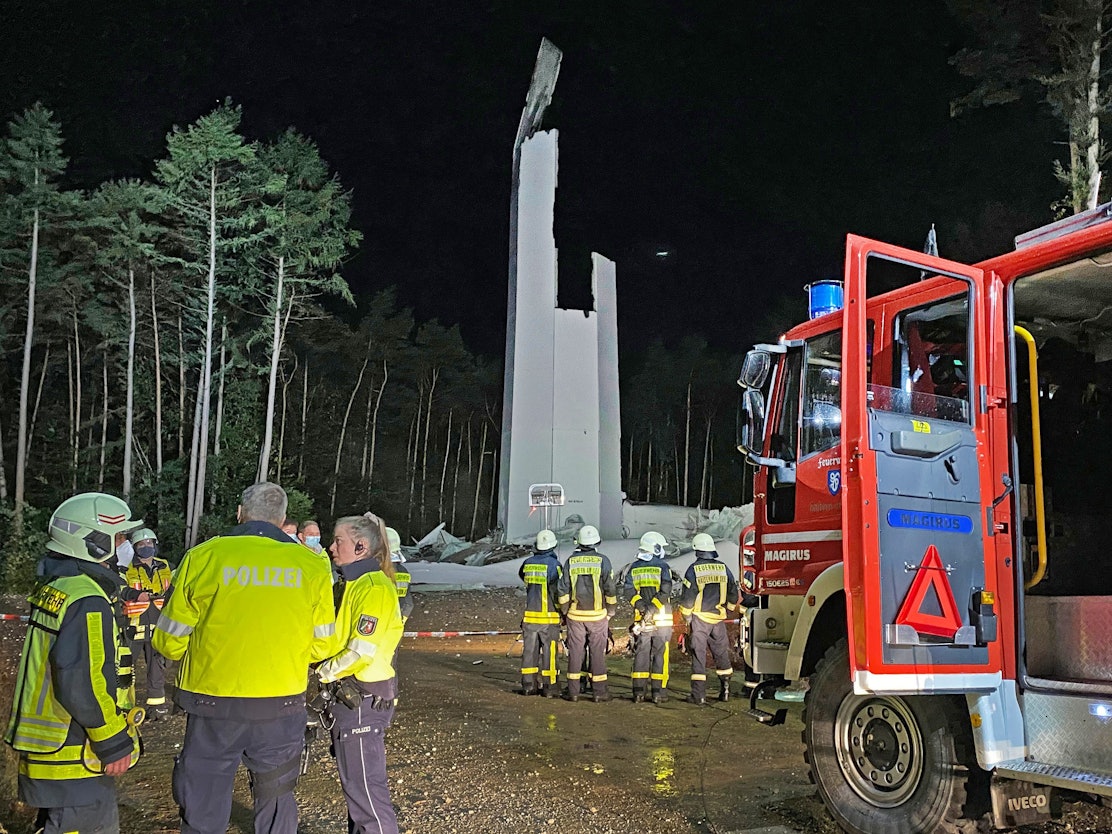 Feuerwehrleute und Polizisten stehen am 29. September 2021 vor den Resten des Turms eines Windrandes. Das fast 240 Meter hohe Windrad ist in sich zusammengestürzt.