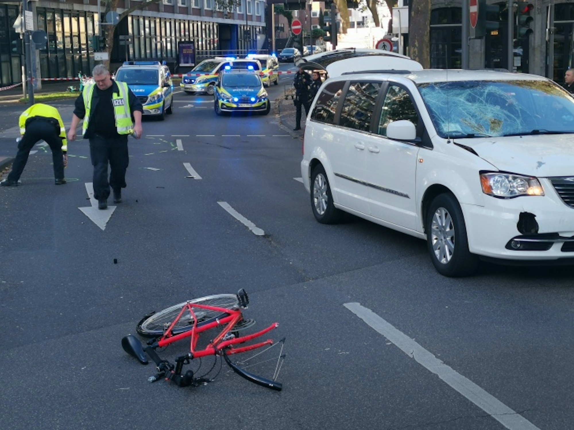 Ein zerfetztes Fahrrad liegt auf der Fahrbahn, Polizisten sichern Spuren.