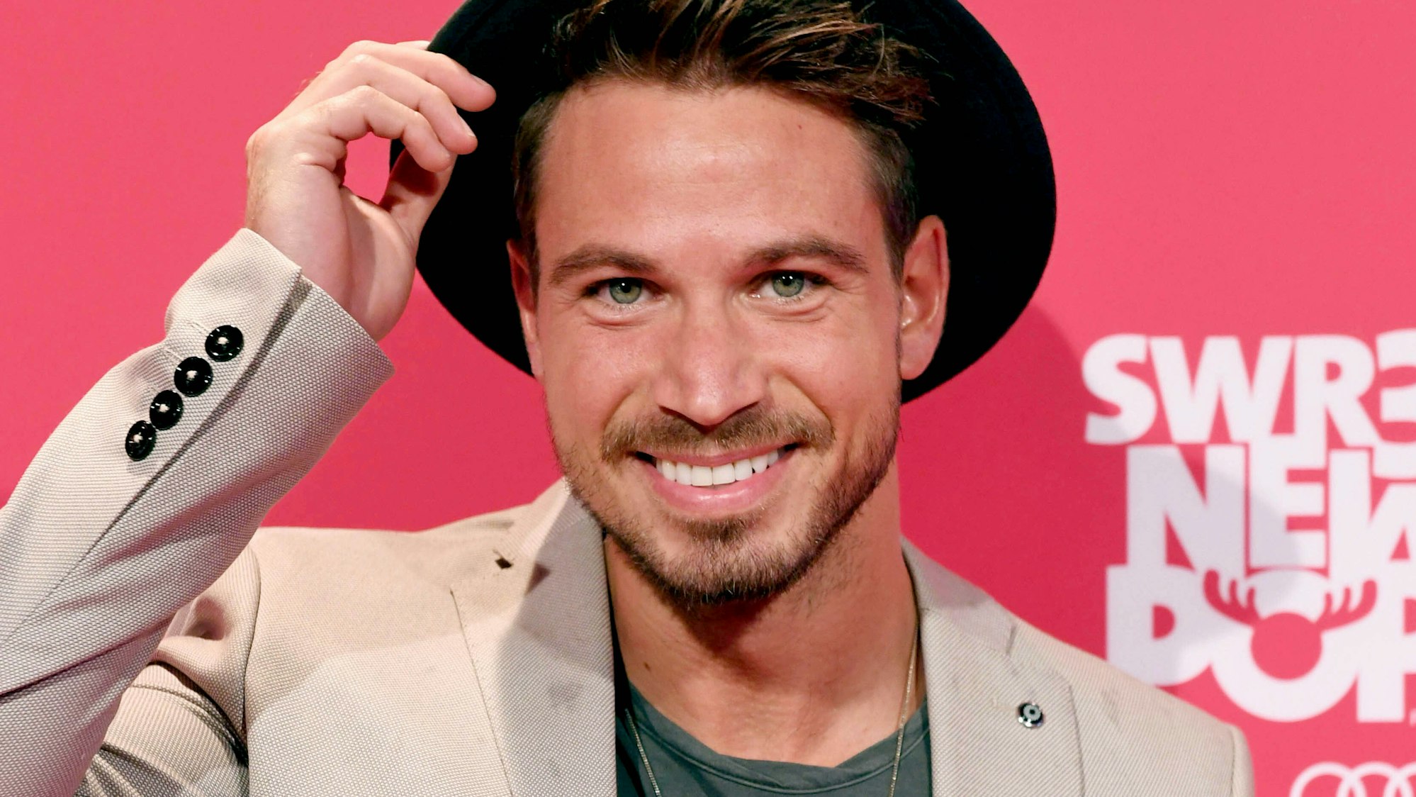 Sebastian Pannek steht vor einem pinken SWR3-Plakat und posiert für die Kamera.