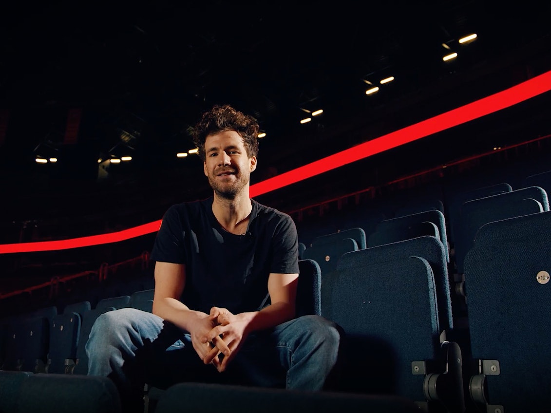 Luke Mockridge sitzt auf einem Stuhl in der Lanxess-Arena.