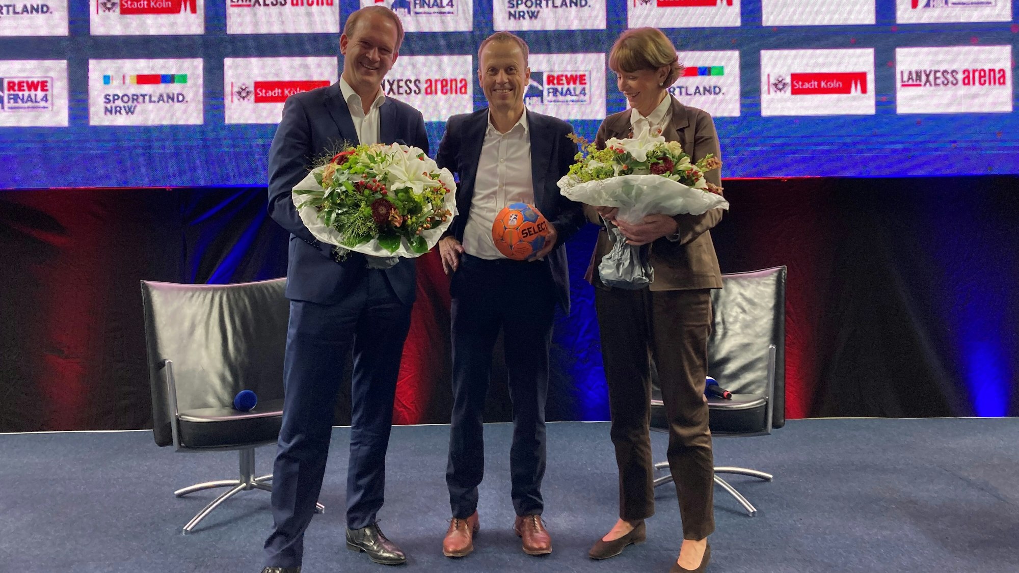 Pressetermin mit Blumen: Stefan Löcher, Frank Bohmann und Henriette Reker.