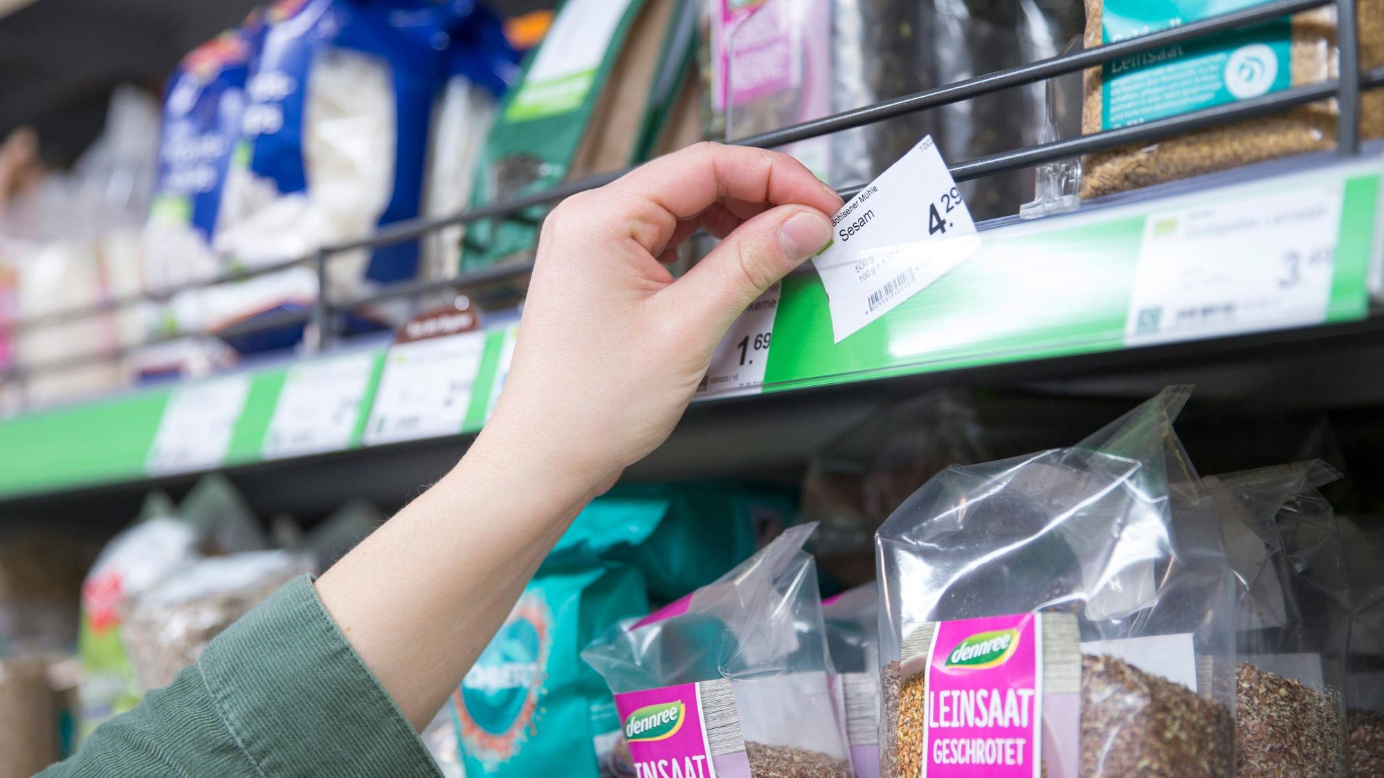 Eine Filialleiterin bestückt vor der Öffnung am frühen Morgen die Regale mit neuer Ware und setzt ein Preisschild ein. Die Inflation in Deutschland hat im September erstmals seit knapp 28 Jahren wieder die Vier-Prozent-Marke überschritten.