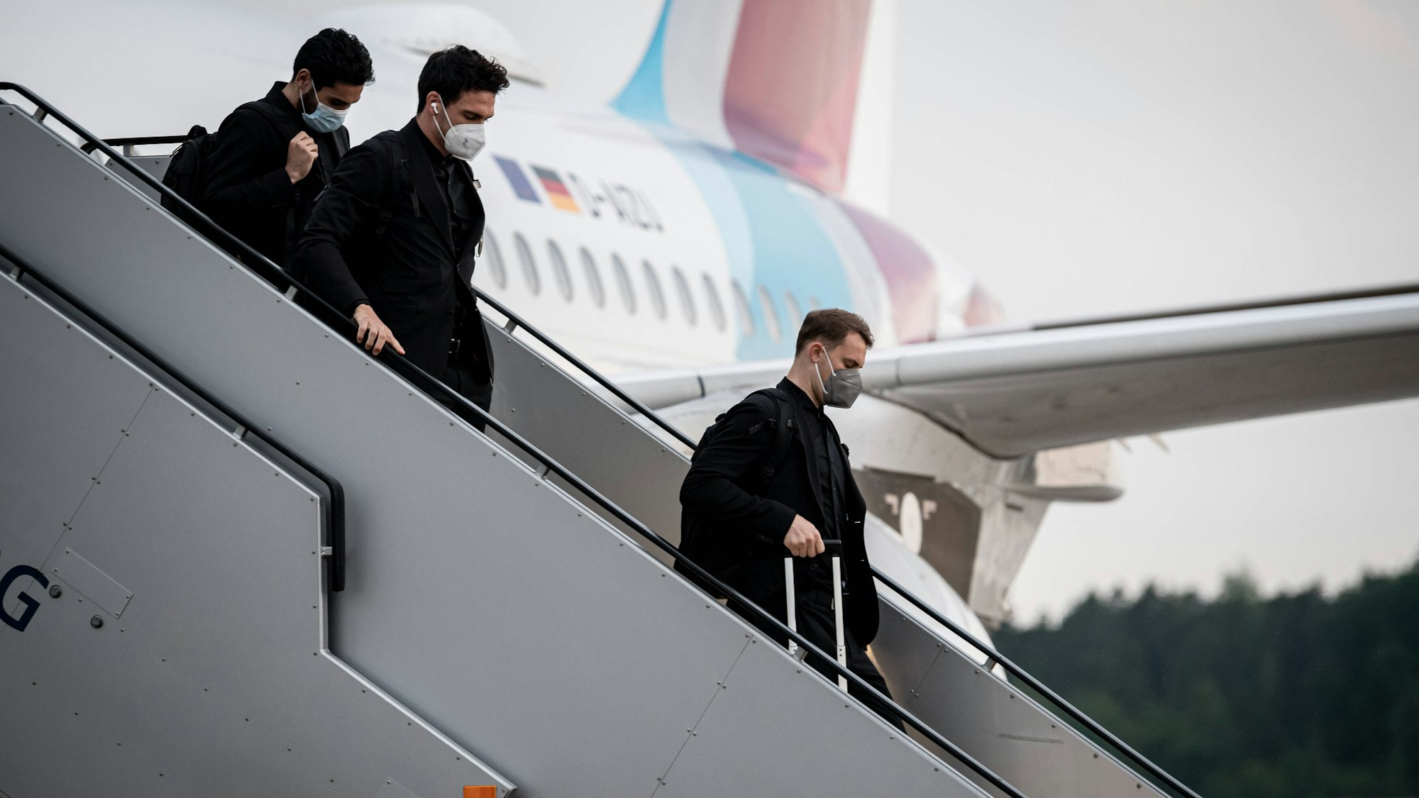 Manuel Neuer, Mats Hummels und Ilkay Gündogan gehen die Treppe am Flugzeug herunter.