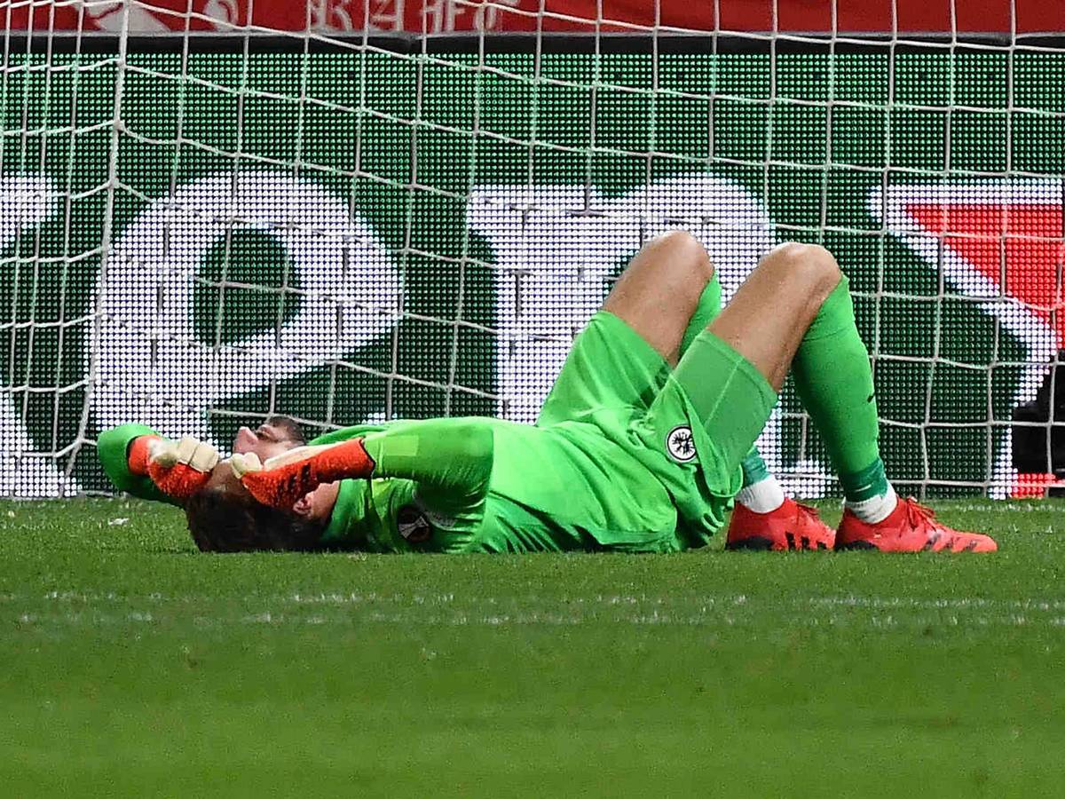 Kevin Trapp von Eintracht Frankfurt wurde von einem Böller der Zuschauer getroffen und liegt am Boden.