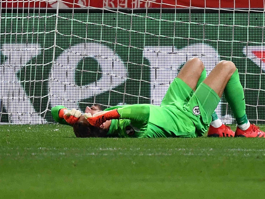 Kevin Trapp von Eintracht Frankfurt wurde von einem Böller der Zuschauer getroffen und liegt am Boden.