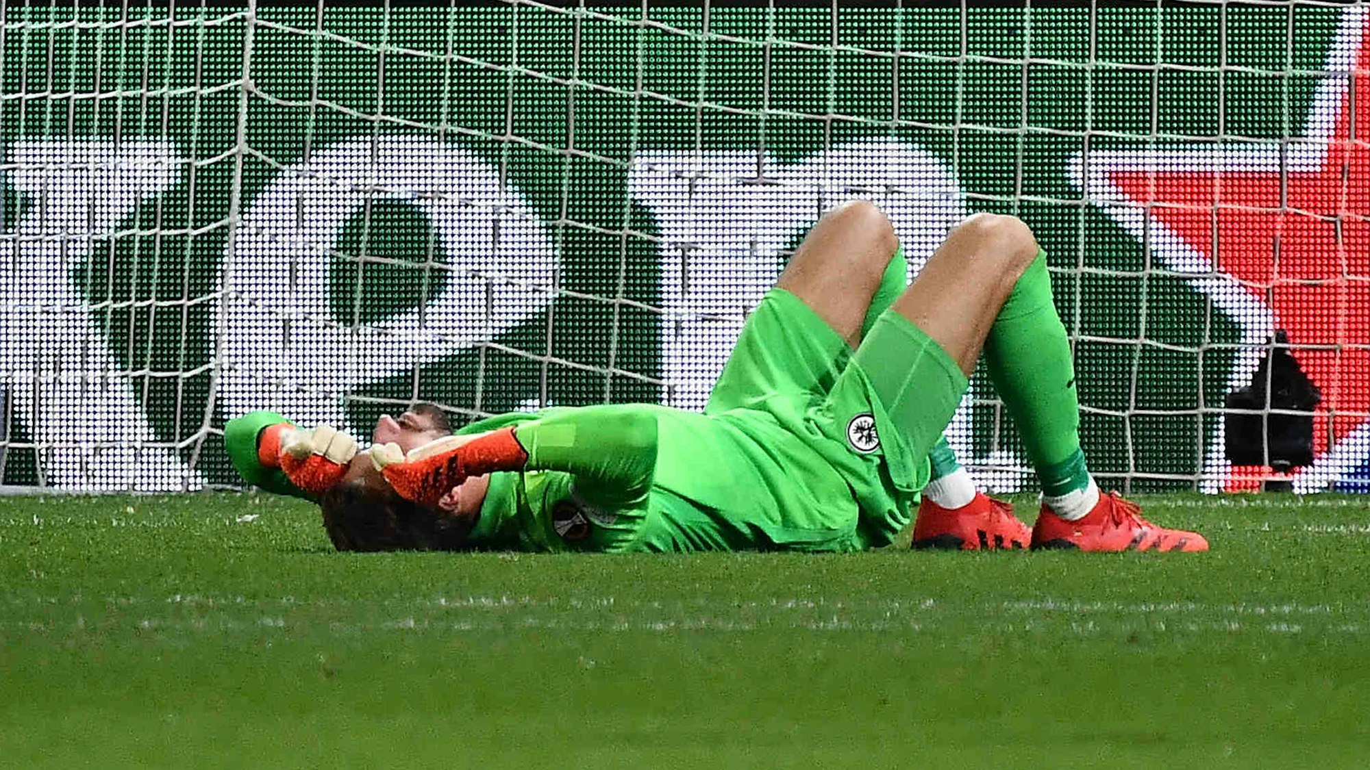 Kevin Trapp von Eintracht Frankfurt wurde von einem Böller der Zuschauer getroffen und liegt am Boden.