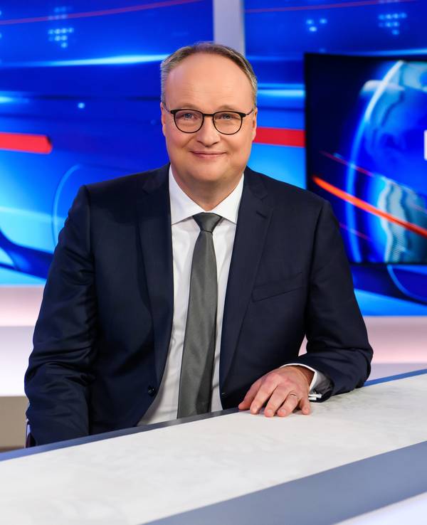 Oliver Welke steht im heute-show-Studio und lächelt in die Kamera.