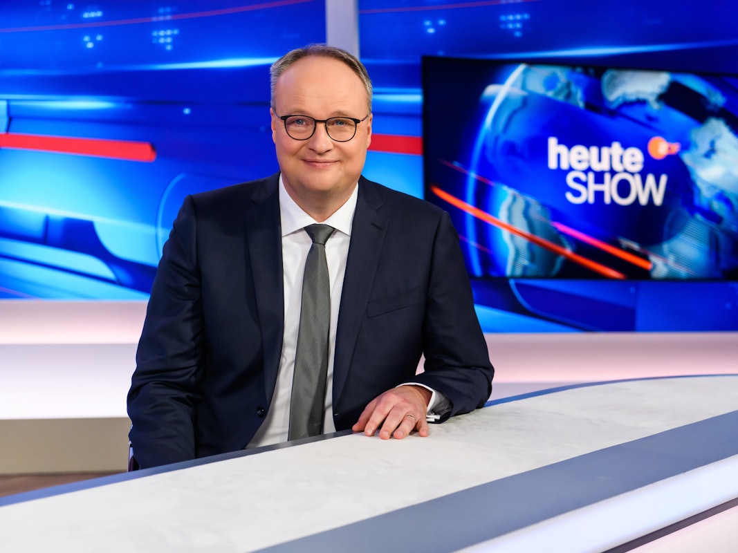 Oliver Welke steht im heute-show-Studio und lächelt in die Kamera.