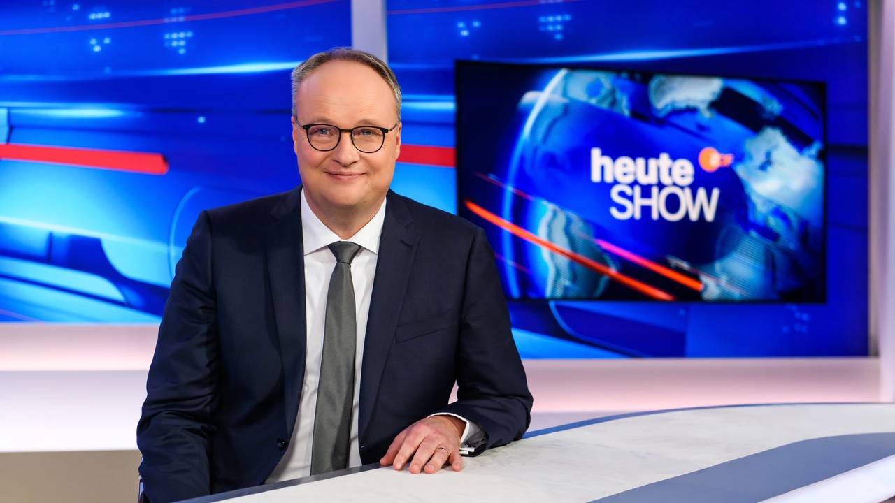 Oliver Welke steht im heute-show-Studio und lächelt in die Kamera.