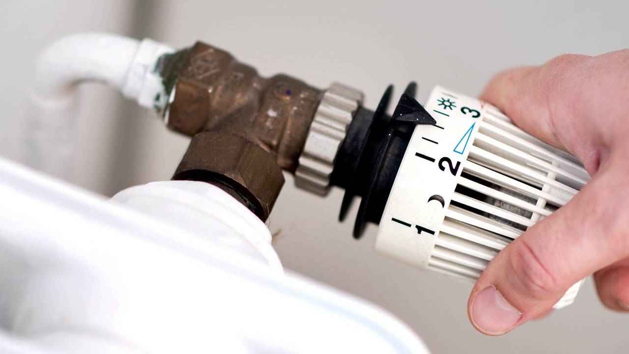 Eine Frau dreht am Thermostat einer Heizung. Die Energiepreise steigen und steigen... Womit hat das zu tun? Was kann die EU dagegen tun?