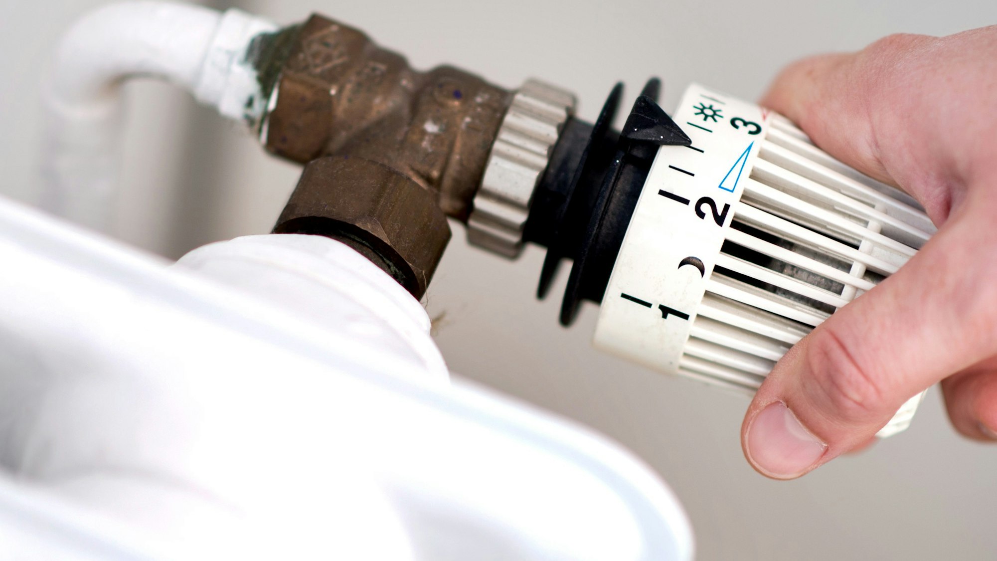 Eine Frau dreht am Thermostat einer Heizung. Die Energiepreise steigen und steigen... Womit hat das zu tun? Was kann die EU dagegen tun?