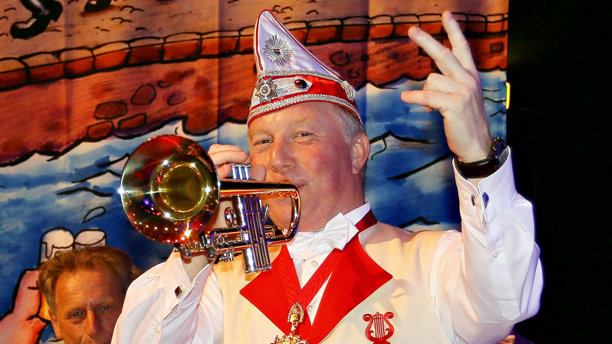 Helmut Blödgen spielt mit einer Hand Trompete, mit der anderen zählt er ein.