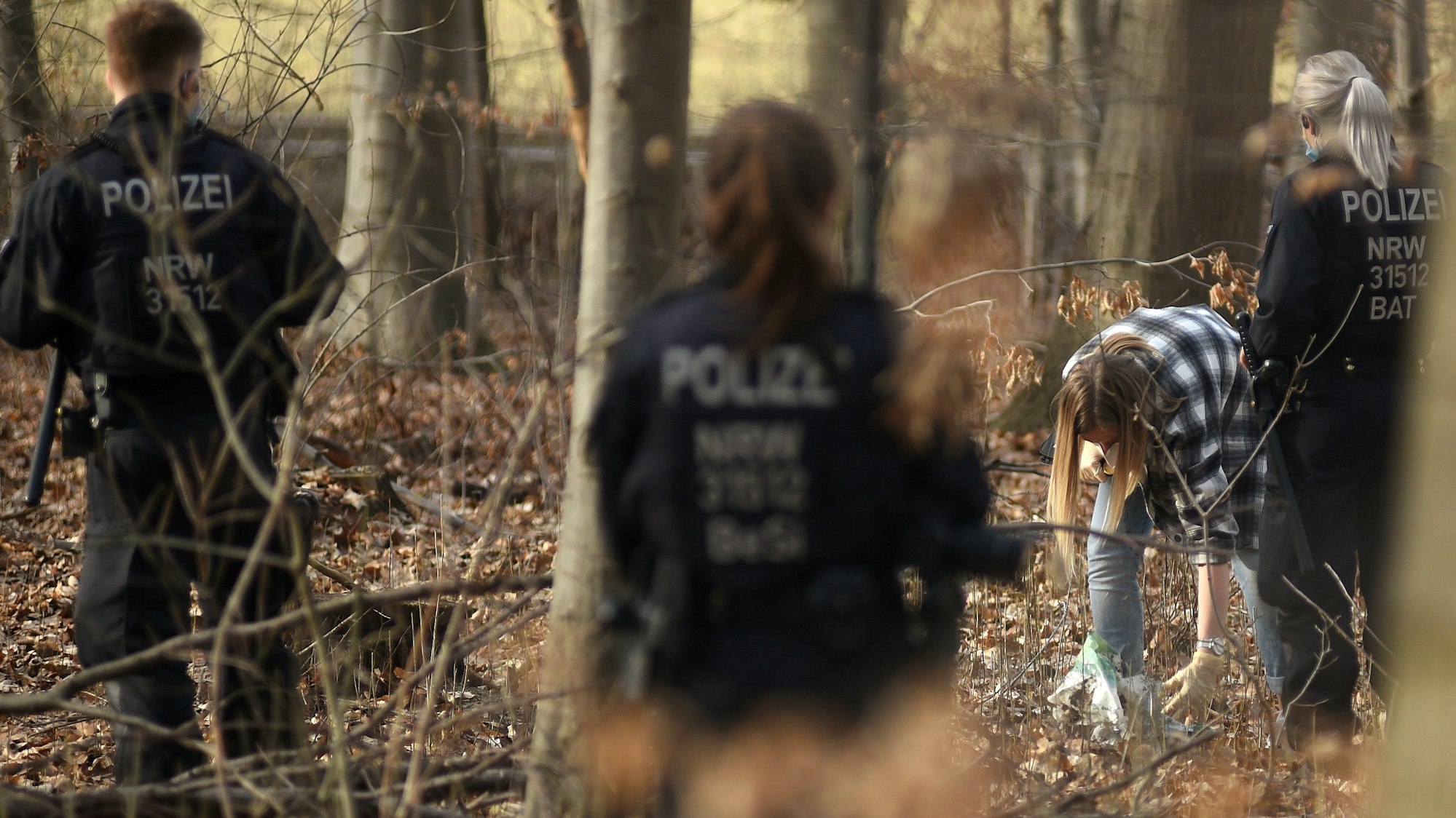 Polizeieinheiten durchsuchen einen Wald.