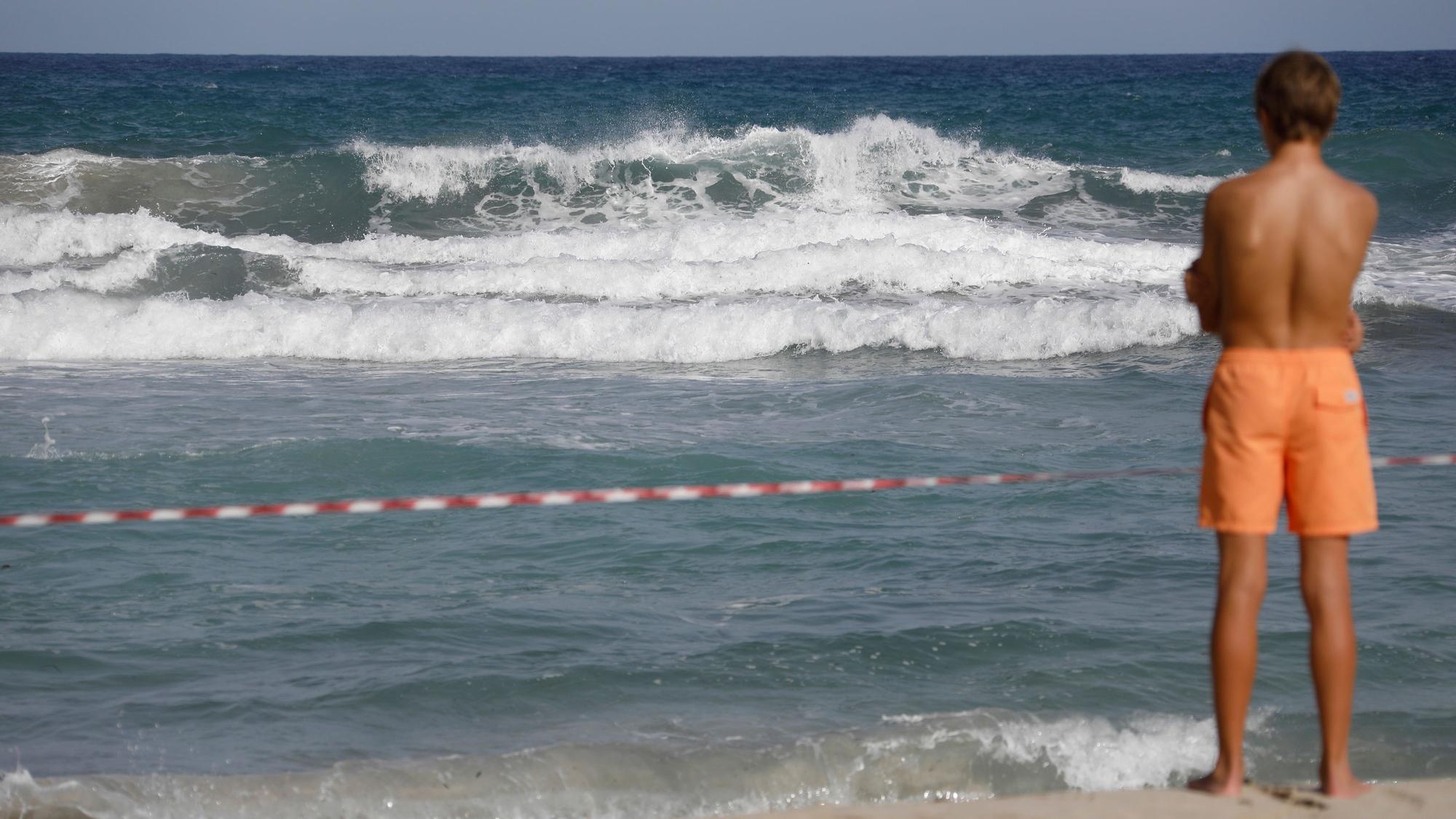 Ein Mann steht am abgesperrten Strand von Cala Mendia in Manacor auf Mallorca.