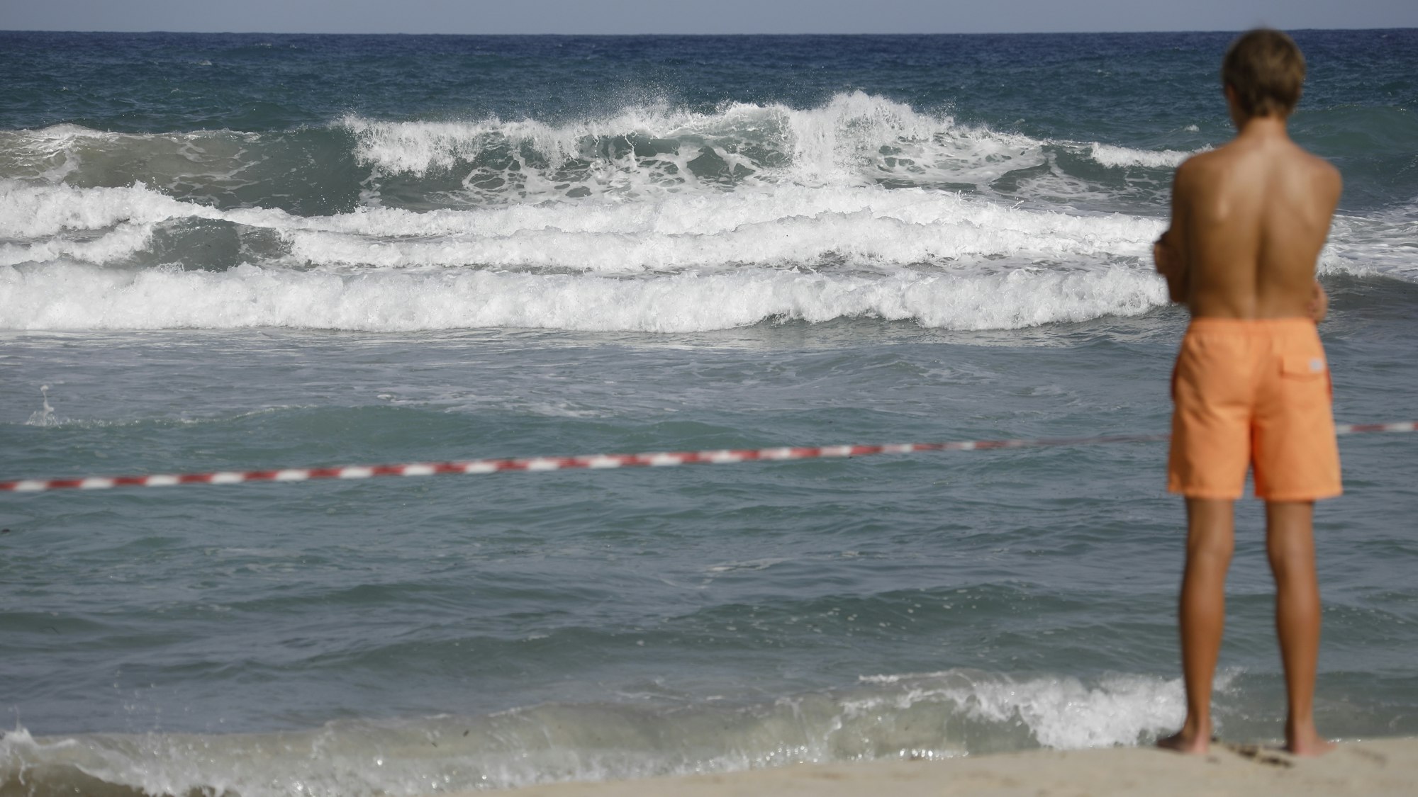 Ein Mann steht an einem abgesperrten Strand.