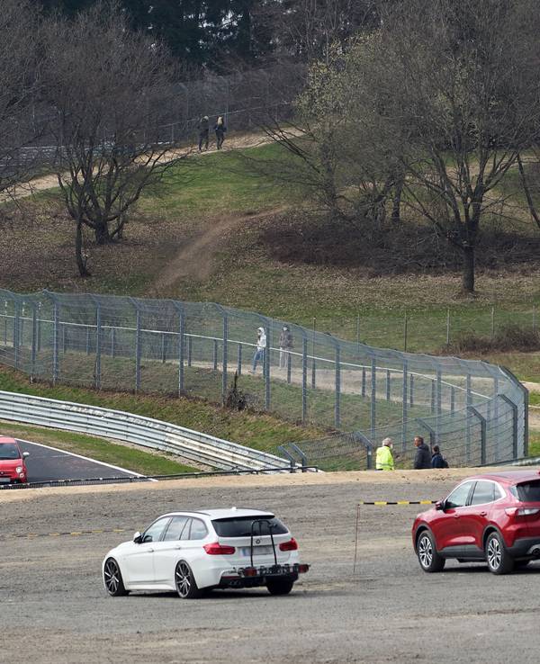 Das Symbolbild zeigt die Nordschleife des Nürburgrings im April 2021, mehrere Autos fahren auf der Strecke, einige Menschen stehen am Rand und schauen zu.
