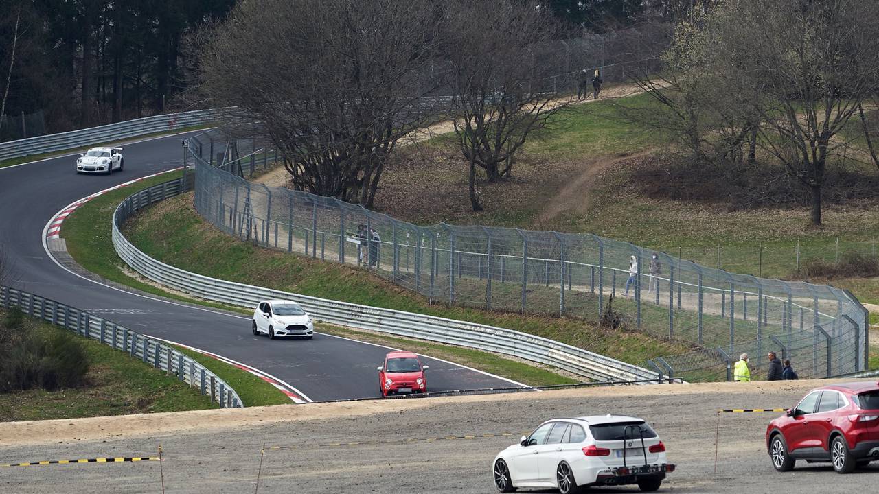 Das Symbolbild zeigt die Nordschleife des Nürburgrings im April 2021, mehrere Autos fahren auf der Strecke, einige Menschen stehen am Rand und schauen zu.