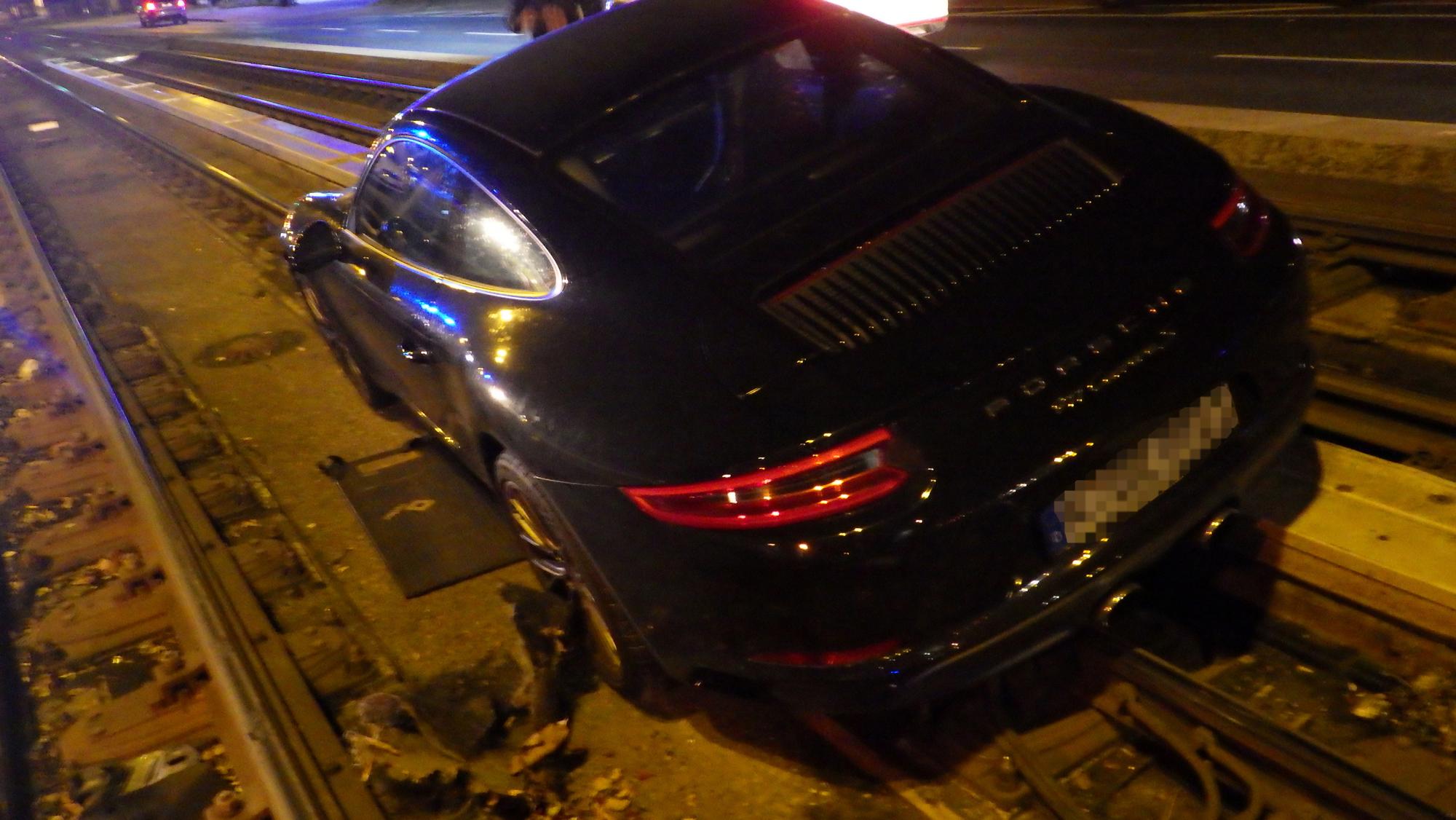 Der Porsche steht mit zwei Rädern im tiefer gelegenen Gleisbett.