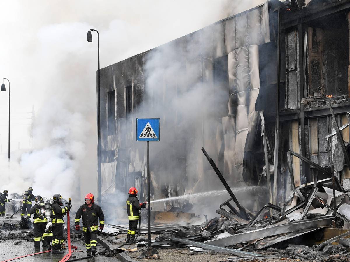 Ein Kleinflugzeug stürzt in Mailand am Sonntag (3. Oktober) nur Augenblicke nach dem Start ab und in ein Bürogebäude. Feuerwehrleute löschen die Trümmer des Gebäudes, Qualm steigt auf.