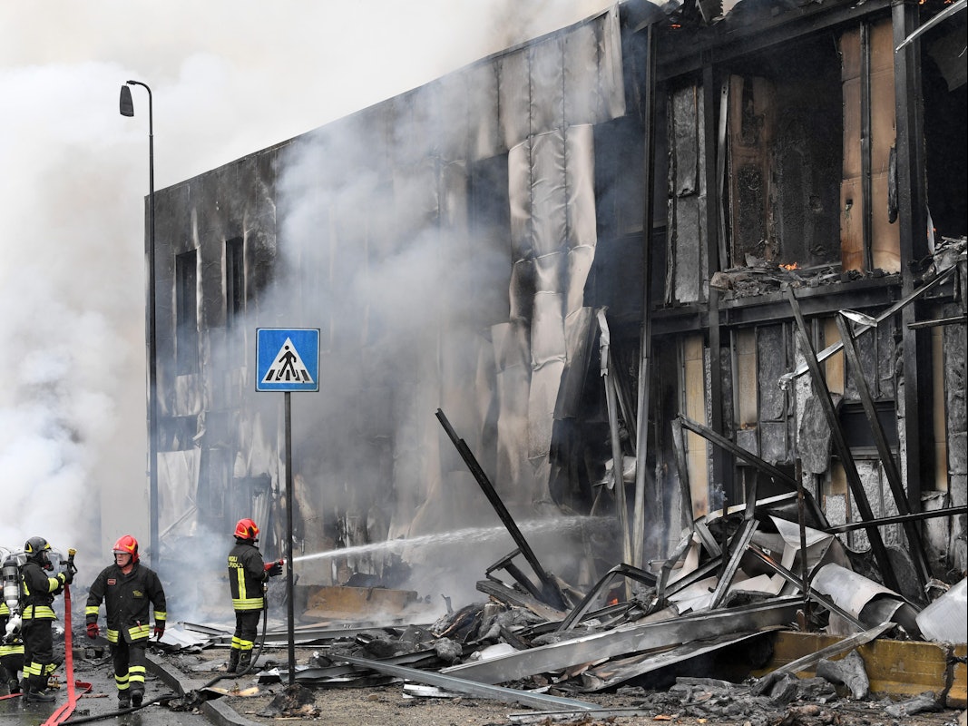 Ein Kleinflugzeug stürzt in Mailand am Sonntag (3. Oktober) nur Augenblicke nach dem Start ab und in ein Bürogebäude. Feuerwehrleute löschen die Trümmer des Gebäudes, Qualm steigt auf.