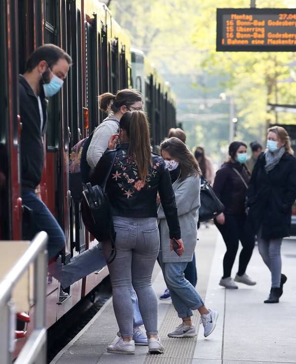 Fahrgäste steigen mit Mundschutz aus und ein eine Stadtbahn in Köln.