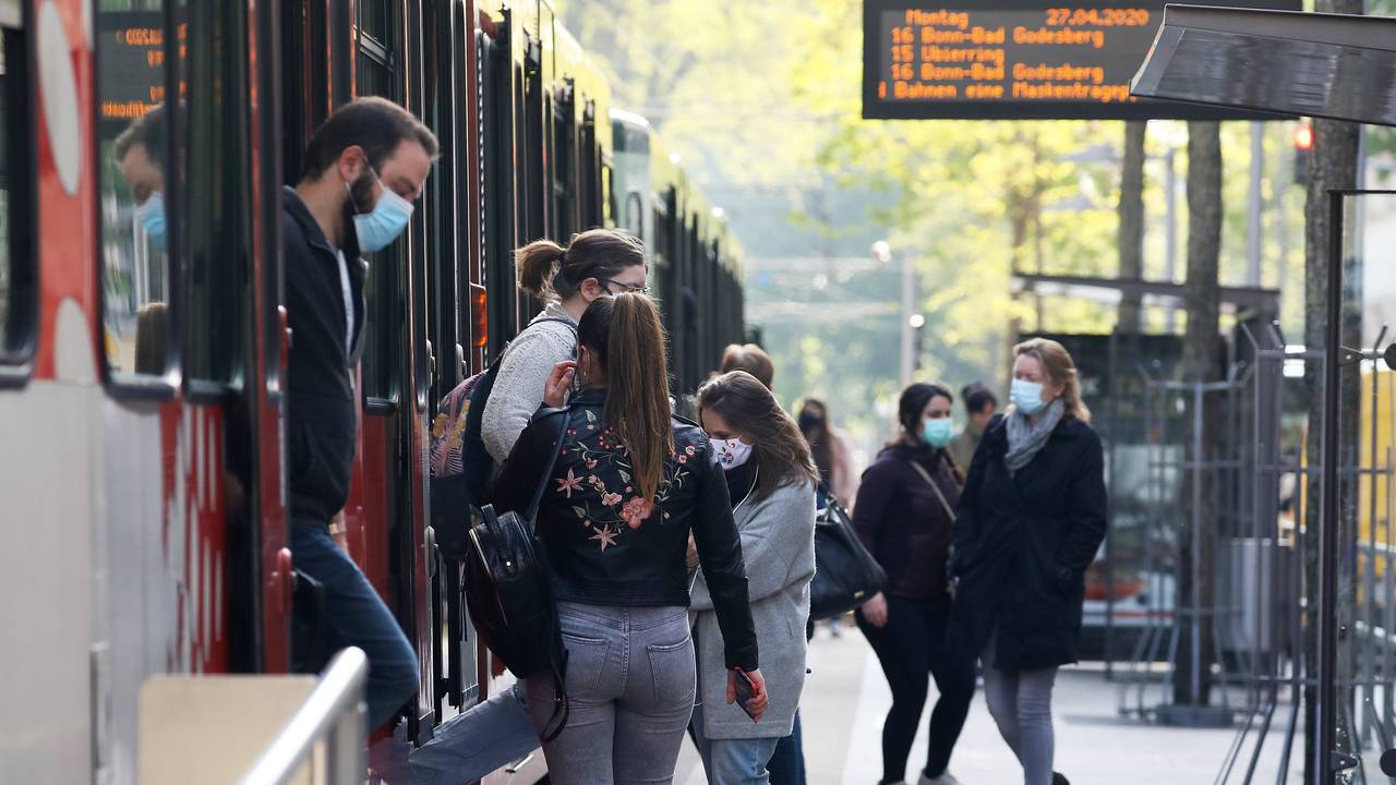 Fahrgäste steigen mit Mundschutz aus und ein eine Stadtbahn in Köln.