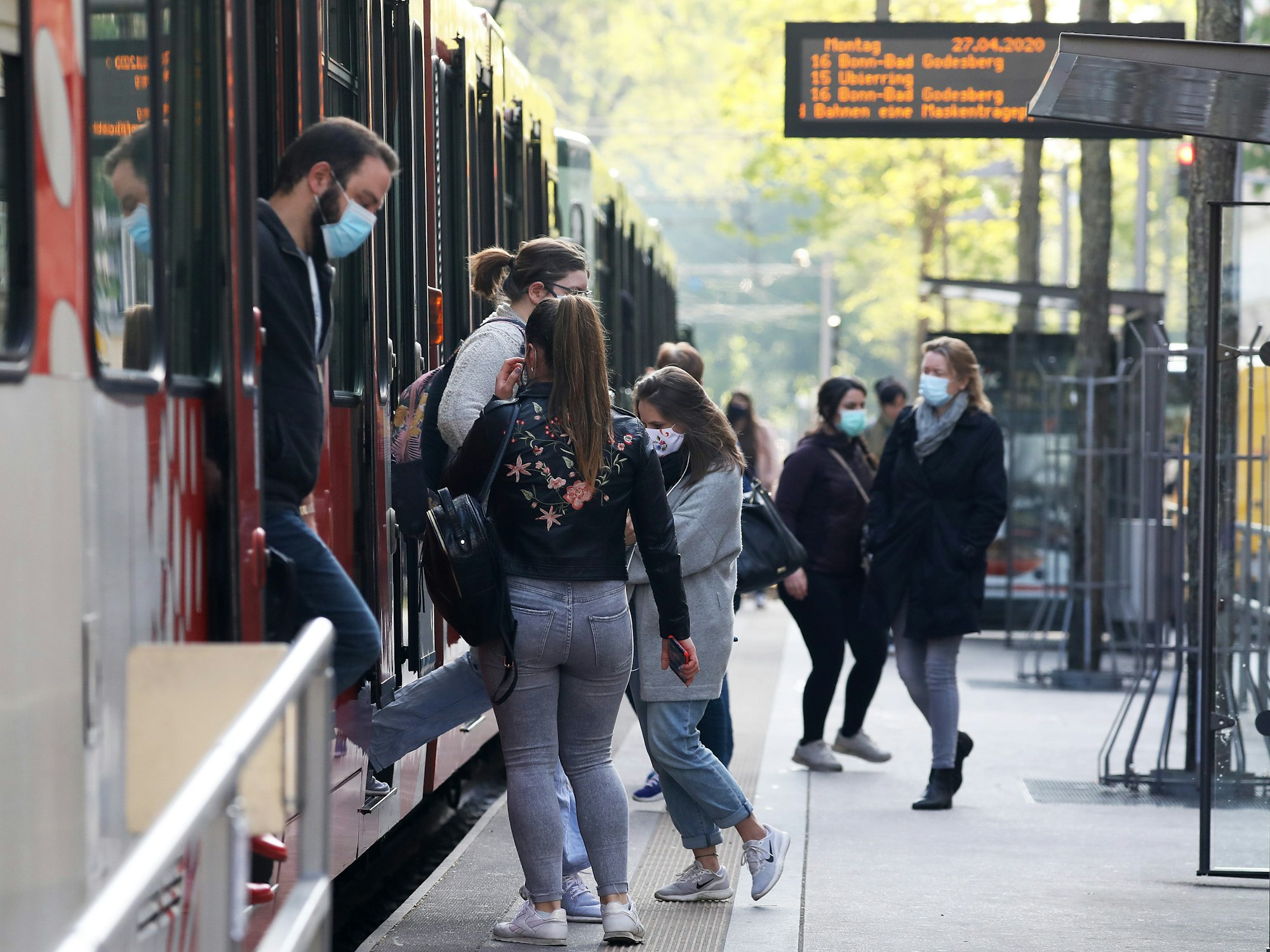 Fahrgäste steigen mit Mundschutz aus und ein eine Stadtbahn in Köln.