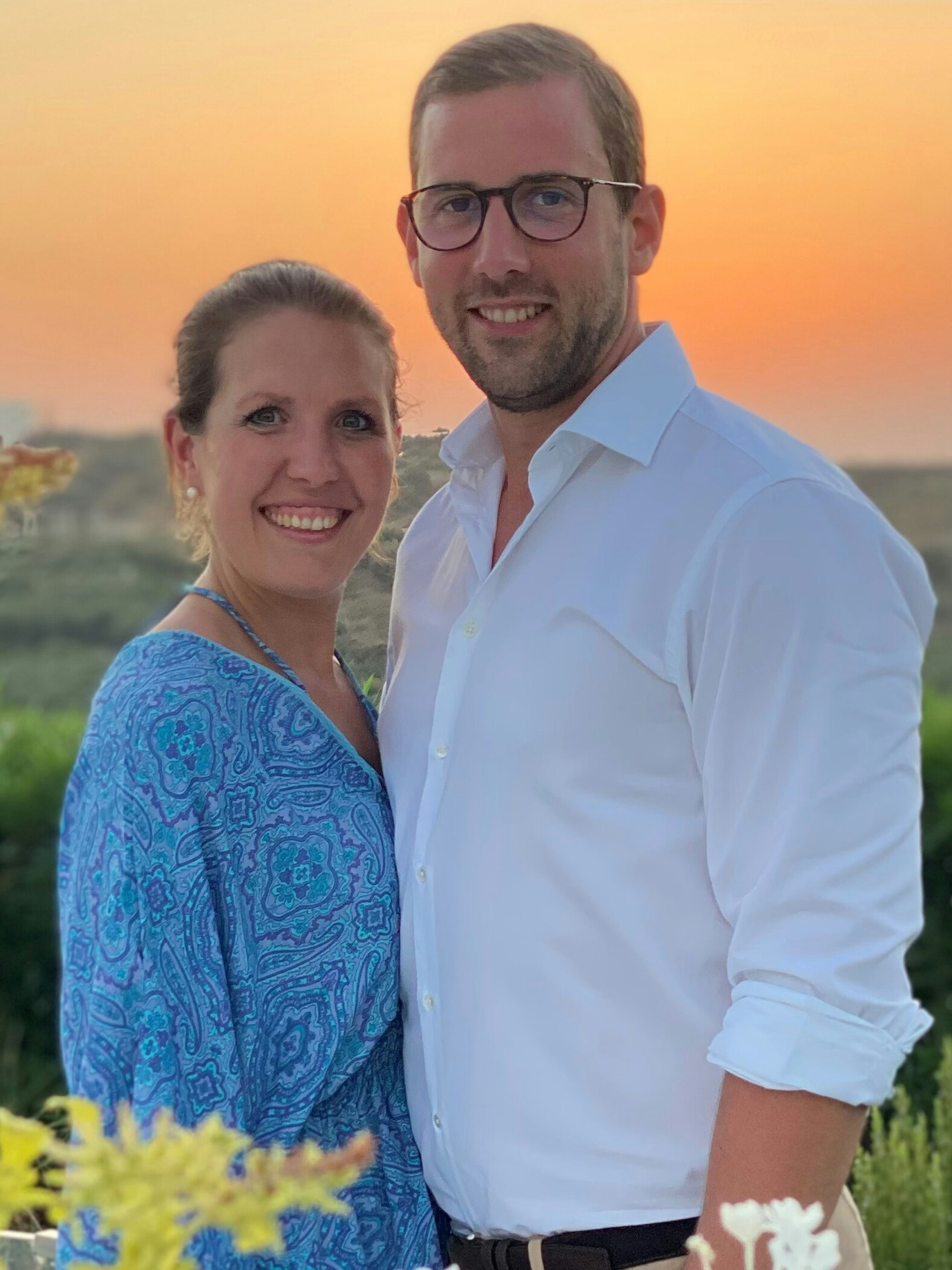 Ann Katrin und Gereon Glasemacher stehen vor einer grünen Landschaft im Urlaub.