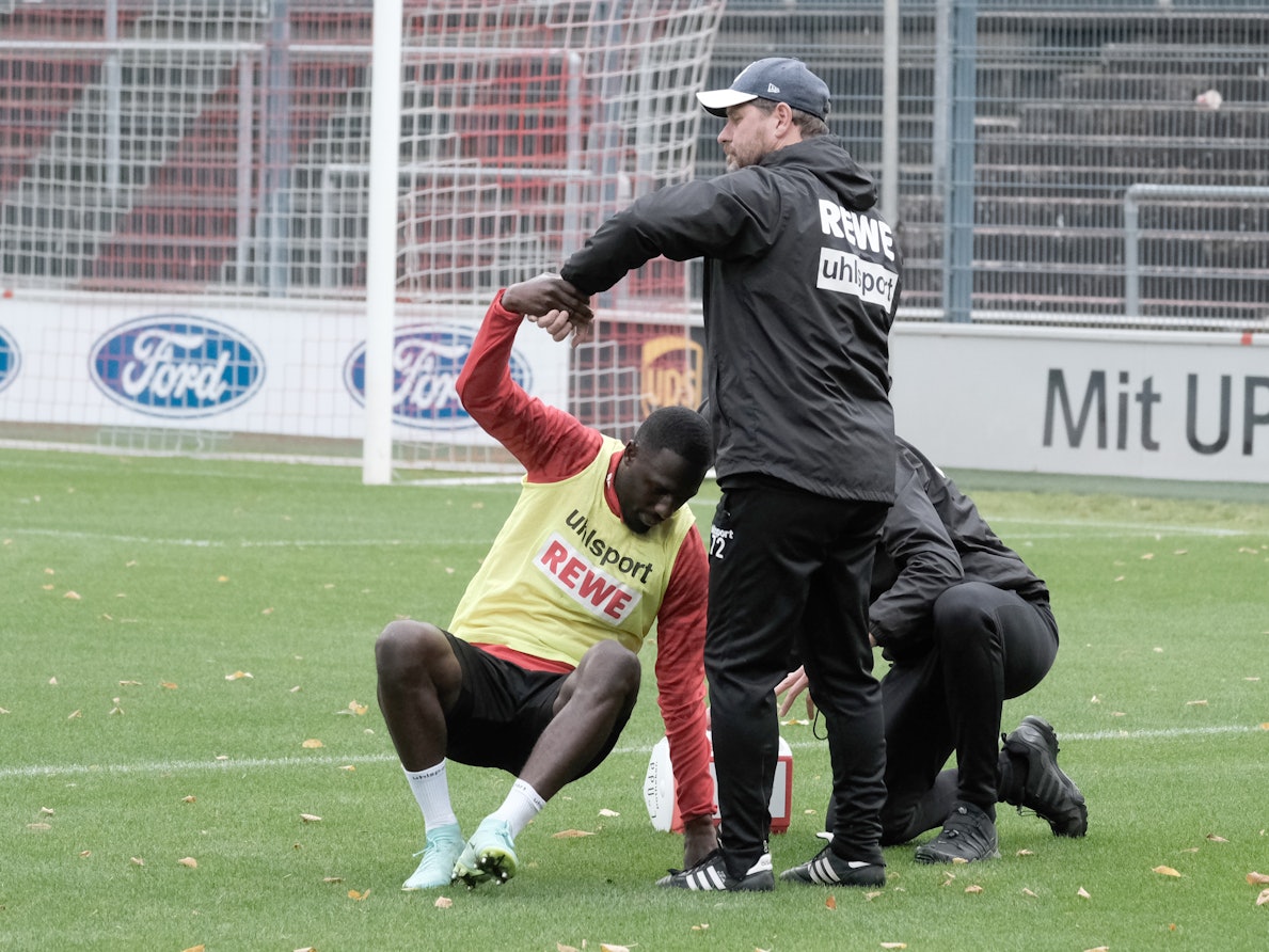 Steffen Baumgart hilft dem angeschlagenen Kingsley Schindler im Training des 1. FC Köln auf die Beine.