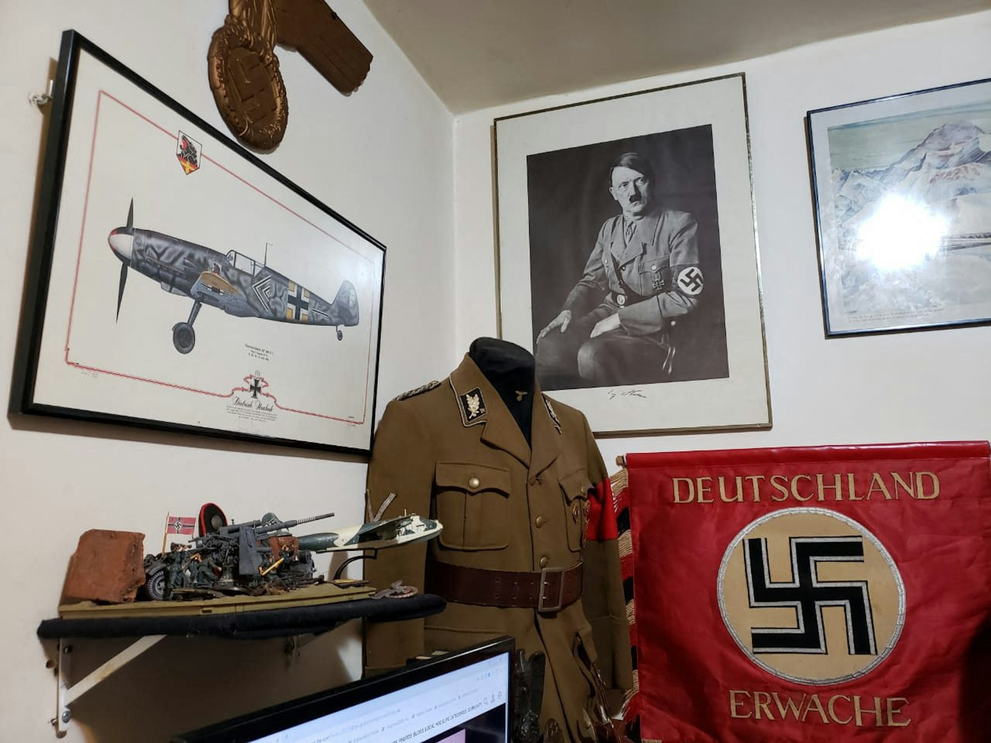 Das Bild zeigt eine Nazi-Uniform und ein Bild mit Adolf Hitler.