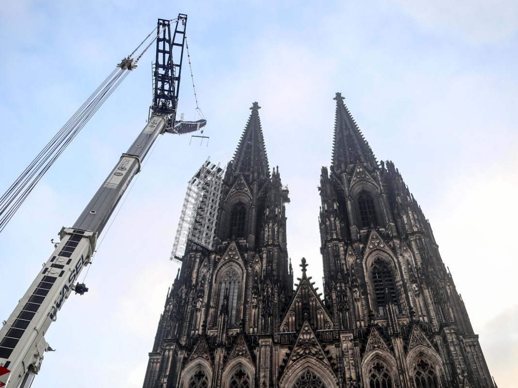 Vor dem Dom und dem Gerüst an der Westfassade steht ein großer Kran