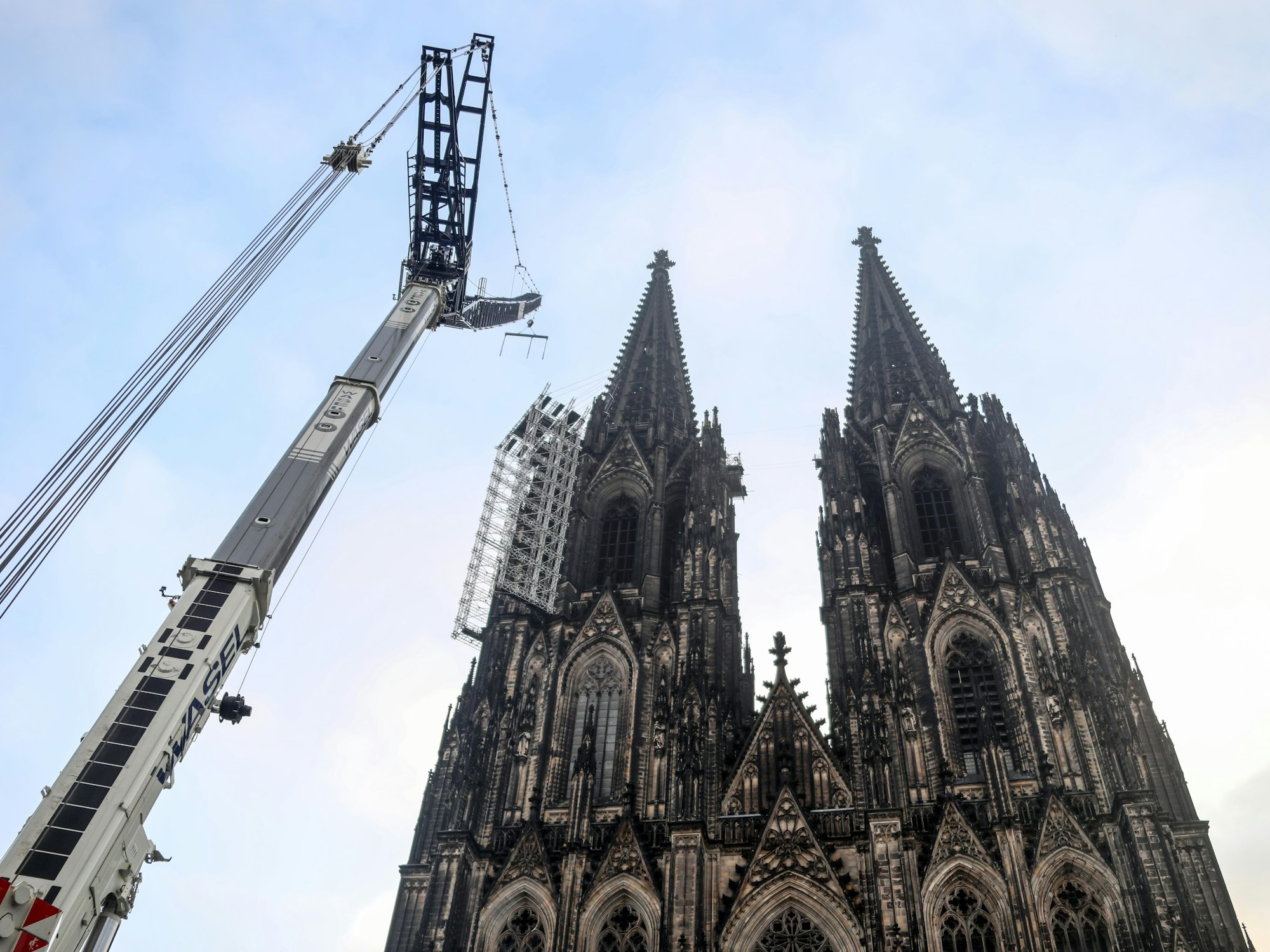 Vor dem Dom und dem Gerüst an der Westfassade steht ein großer Kran