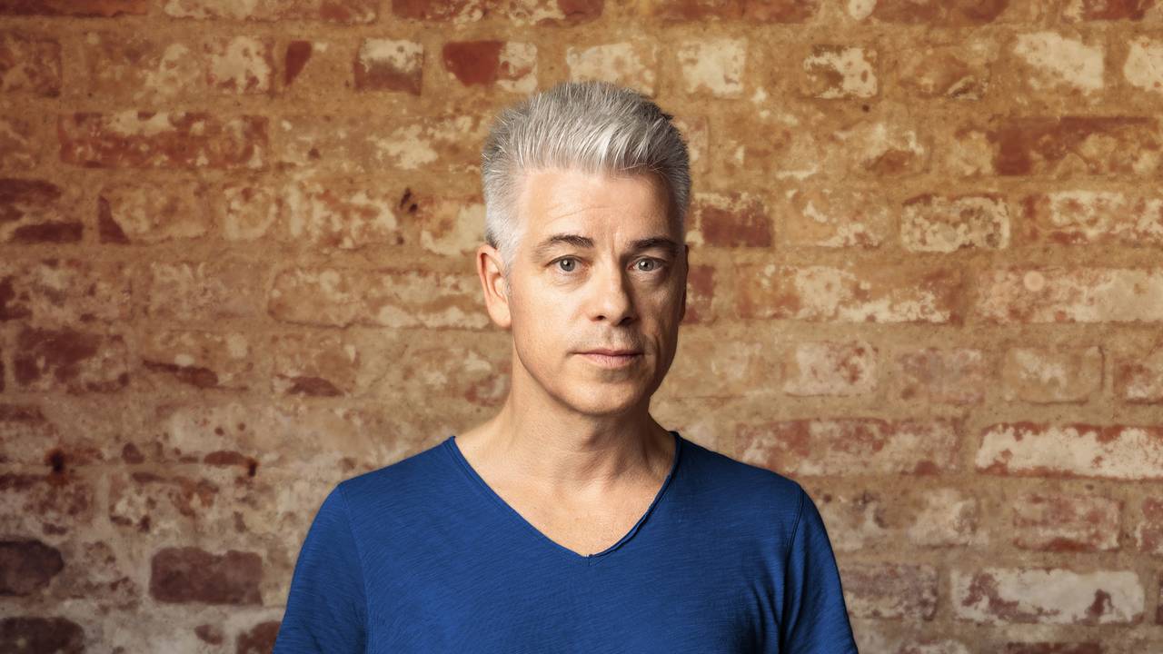 Comedian Michael Mittermeier steht mit ernstem Blick vor einer Steinwand und schaut in die Kamera.