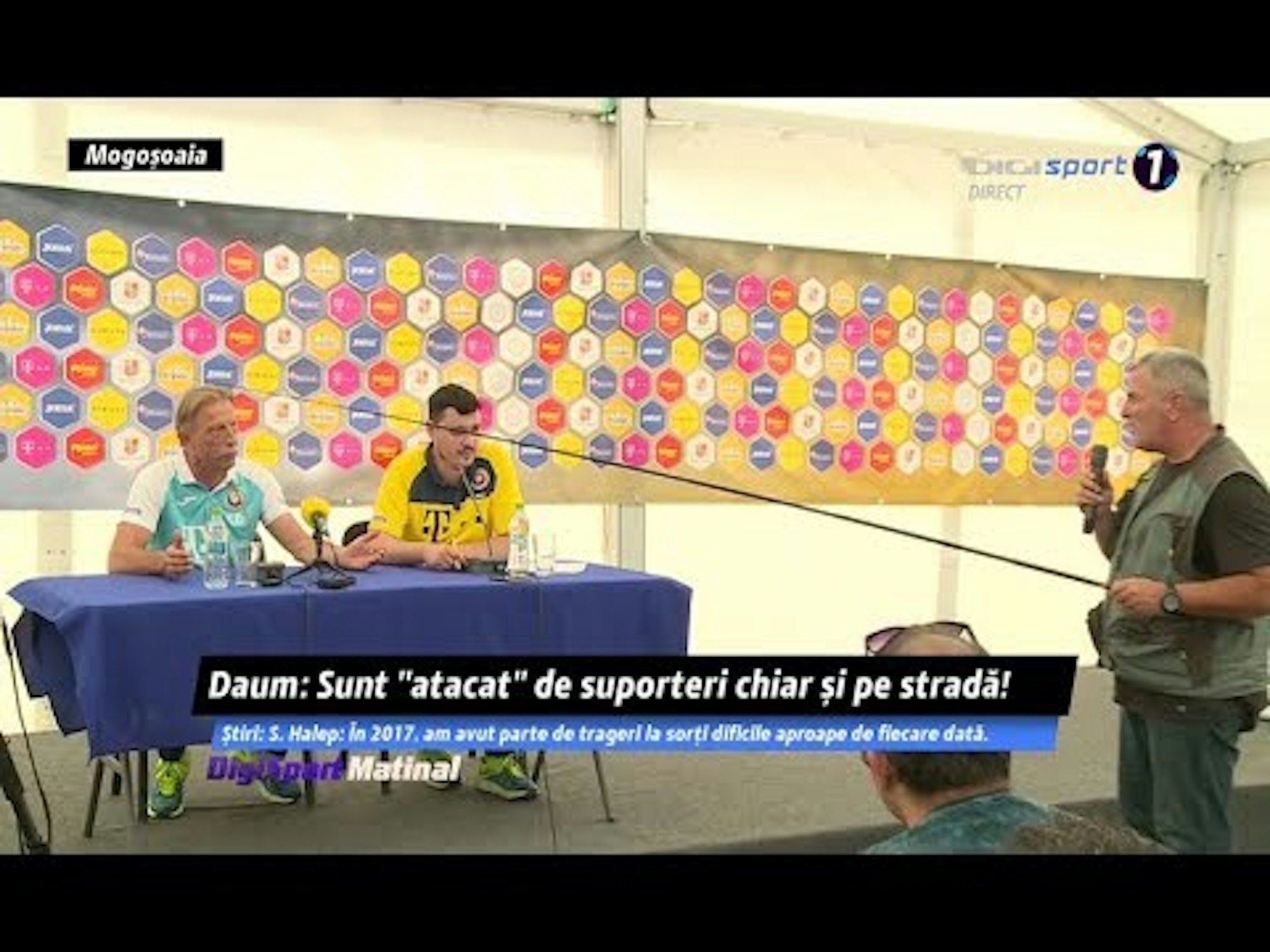 Ein Reporter mit einer Angel in der Hand stellt Christoph Daum eine Frage.