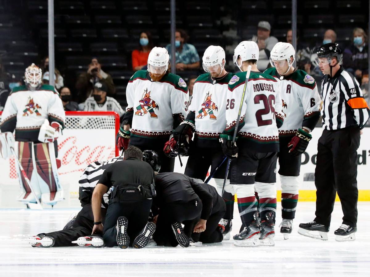 Die Spieler der Arizona Coyotes versammeln sich bei einem NHL-Vorbereitungsspiel um den am Boden liegenden Schiedsrichter Ryan Gibbons, der von Medizinern behandelt wird.