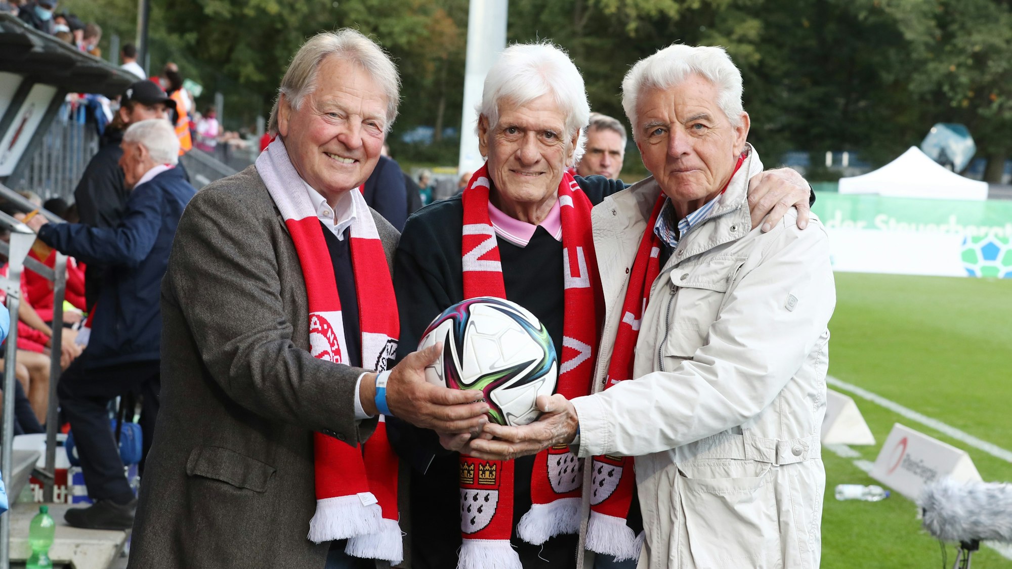 Karl-Heinz Thielen, Wolfgang Fahrian und Erich Ribbeck stehen vor der Tribüne.