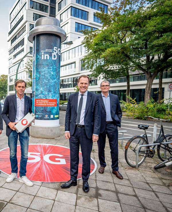 Alle Beteiligten stehen vor einer Litfaßsäule in Düsseldorf.