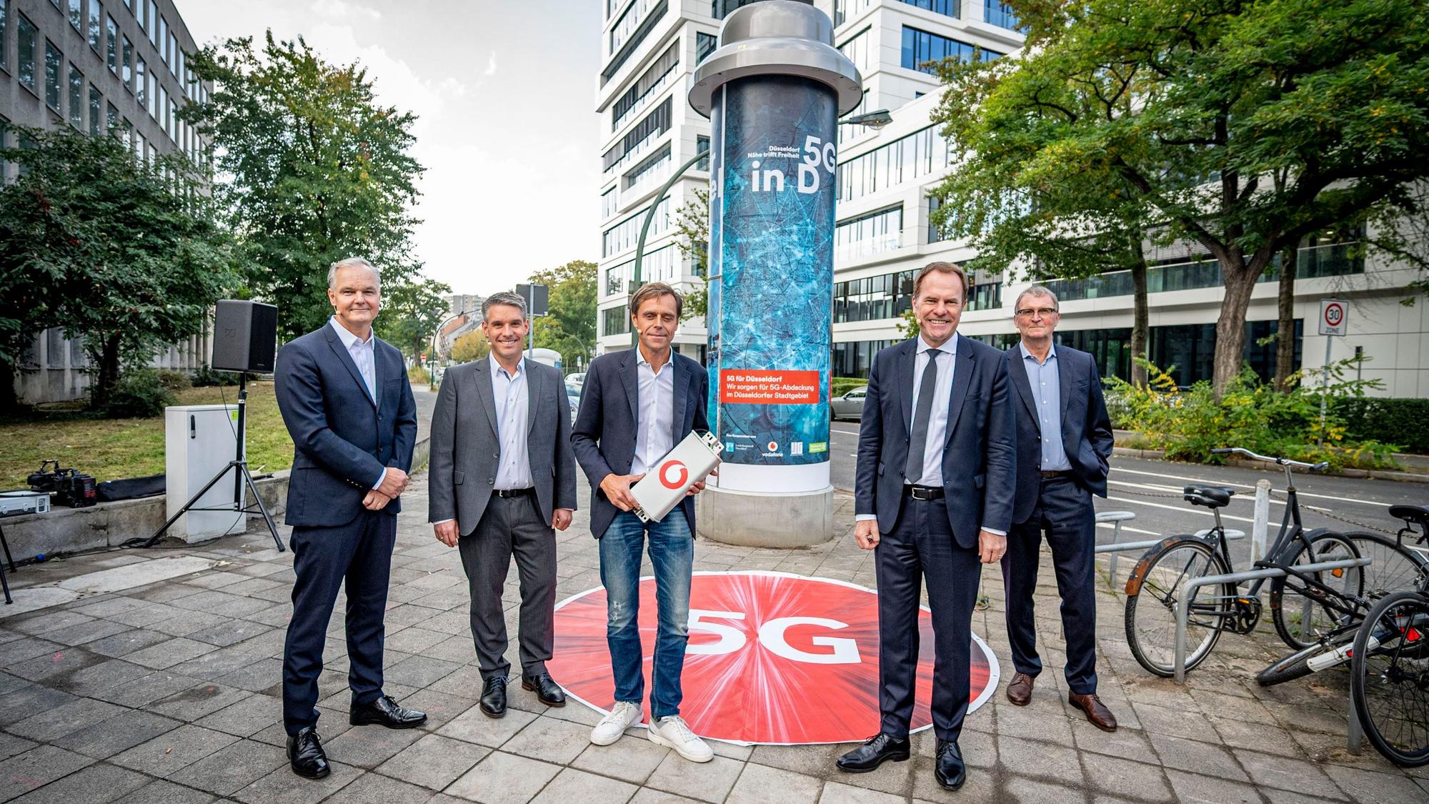 Alle Beteiligten stehen vor einer Litfaßsäule in Düsseldorf.