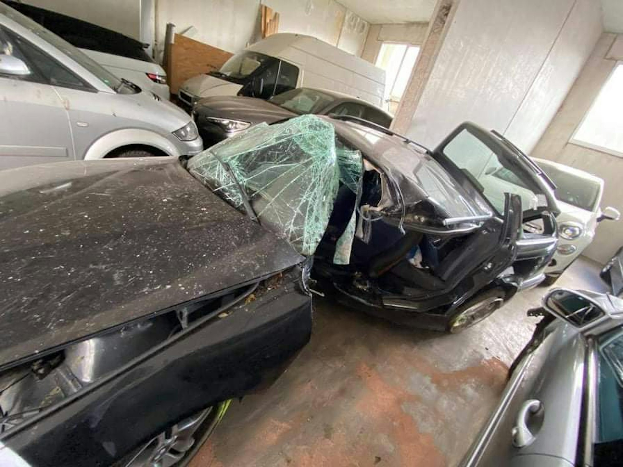 Ein demoliertes Auto steht in einer Garage.