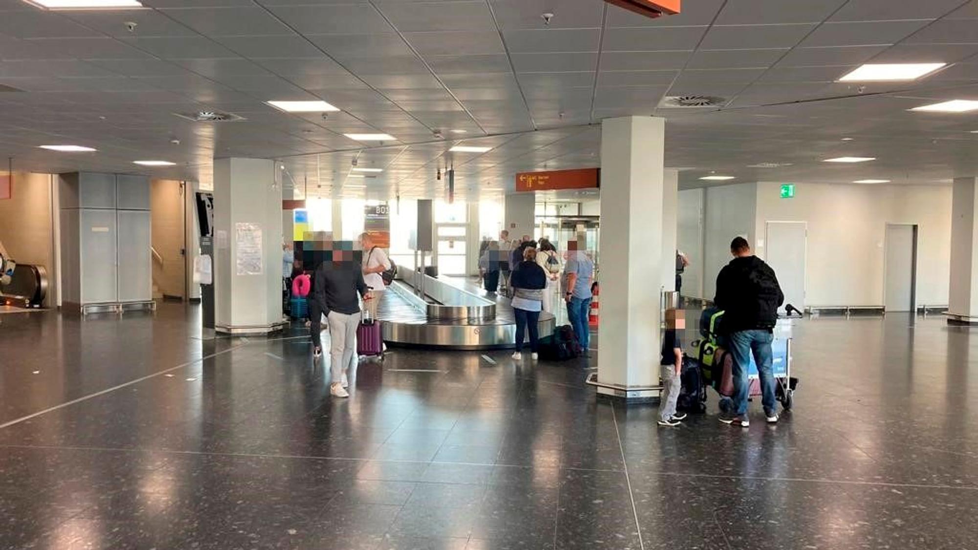 Menschen stehen an einem Gepäckband im Köln-Bonner Flughafen