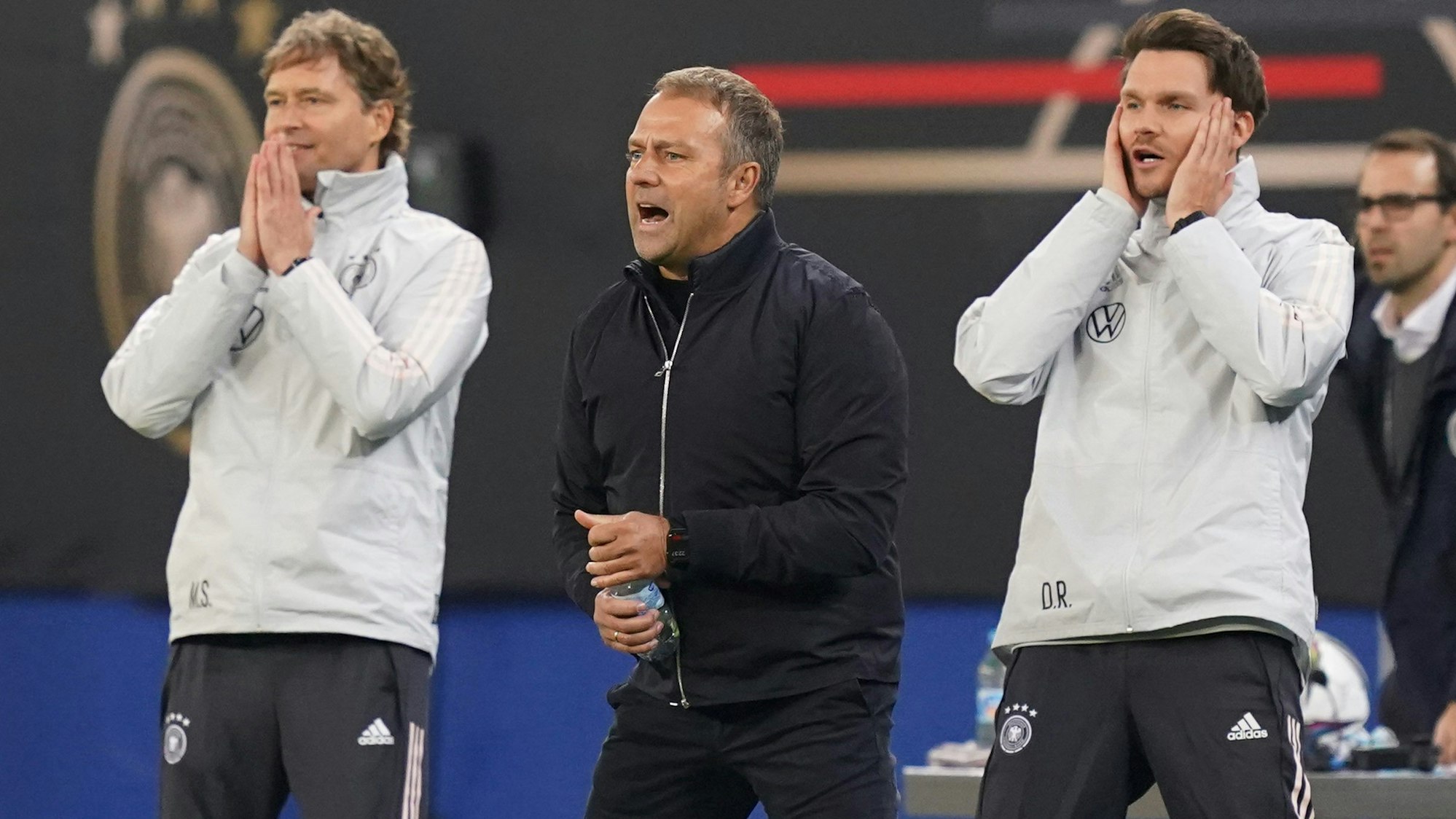 Bundestrainer Hansi Flick (M) sowie die Assistenztrainer Marcus Sorg (l) und Danny Röhl agieren an der Seitenlinie.