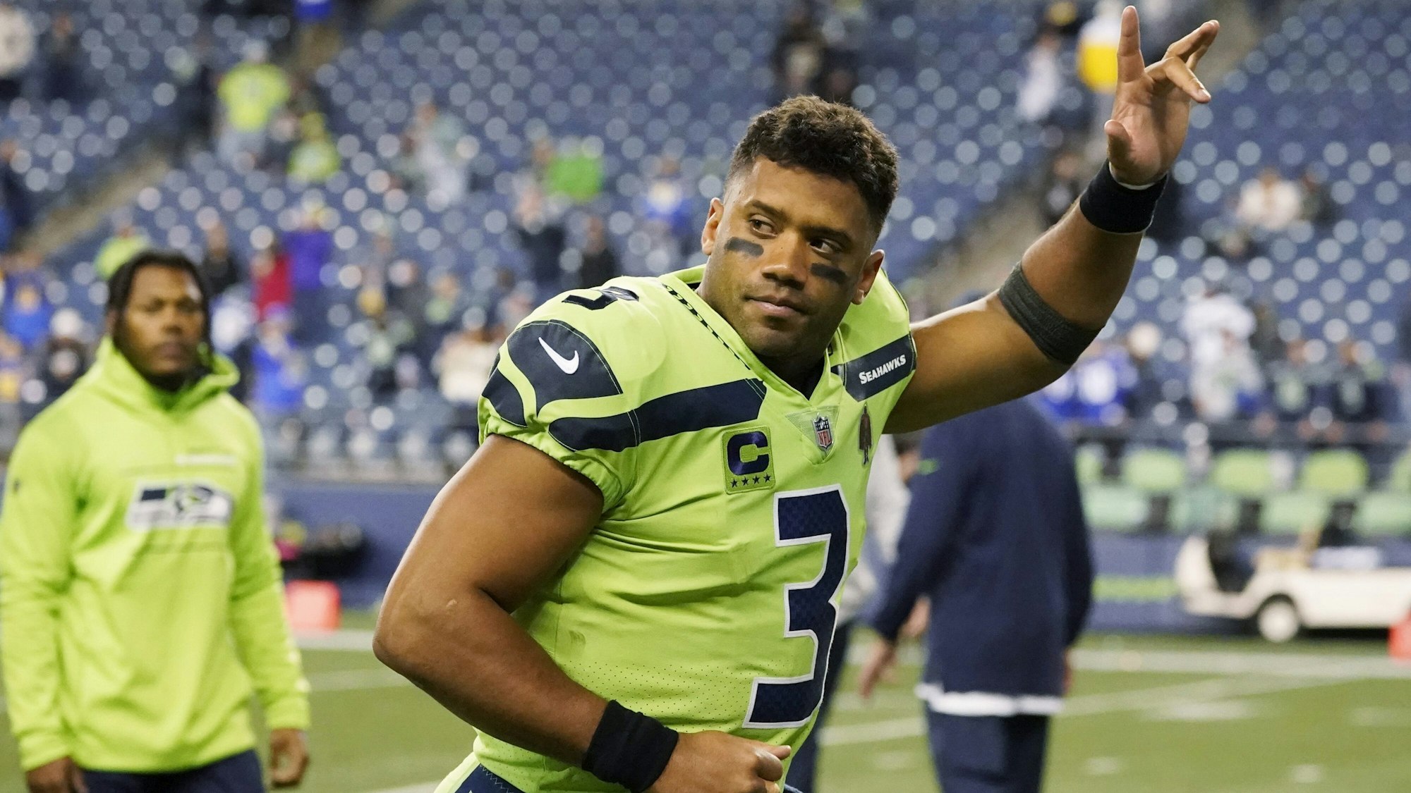 Russell Wilson hält beim Spiel der Seattle Seahawks den linken Arm nach oben.