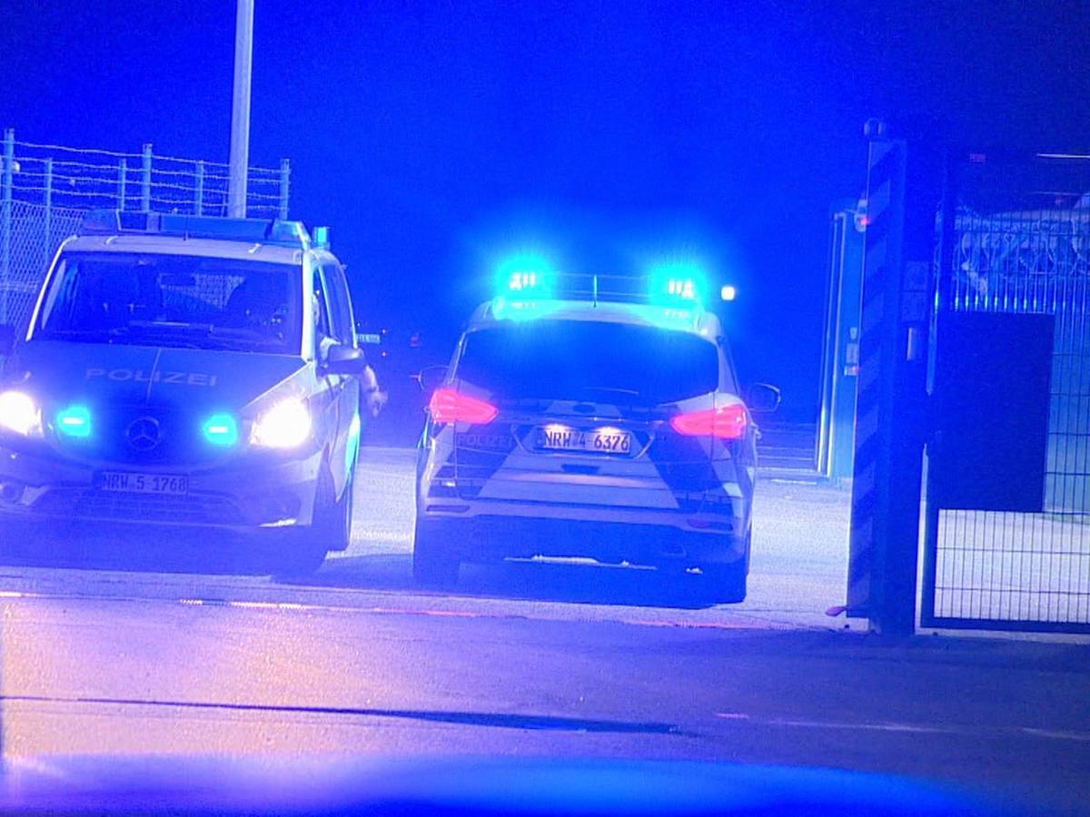 Polizisten passieren in Polizeifahrzeugen ein Tor am Flughafen Weeze, wo ein Auto einen Zaun an einer Rollbahn durchbrochen hat.