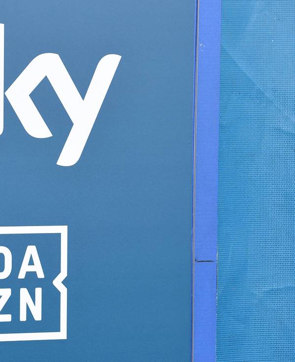 Die Logos der TV-Anbieter Sky und DAZN sind auf eine Tafel gedruckt.